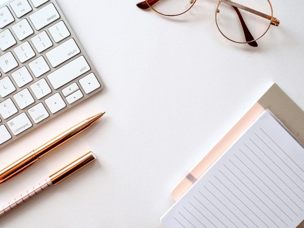 image of desk with keyboard, pen and pad of paper.